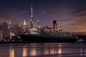 Cruise ship docked with city skyline at night.