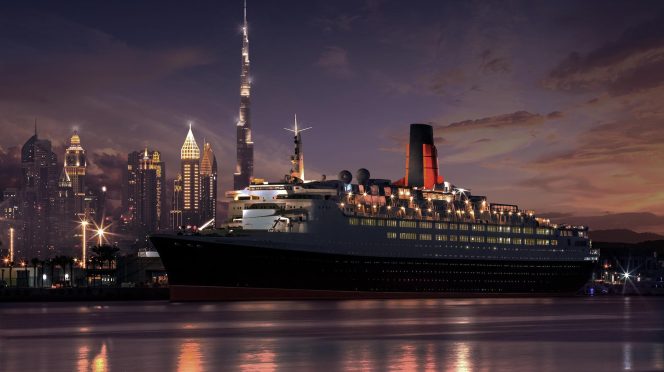 Cruise ship docked with city skyline at night.