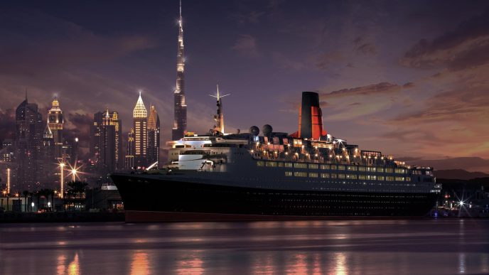 Cruise ship docked with city skyline at night.