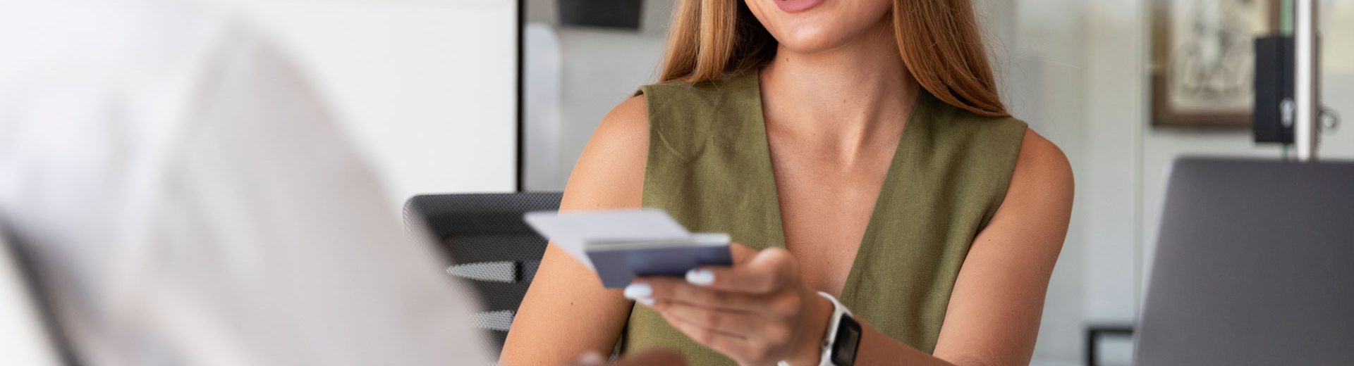 Woman smiling, handing over a bank card.