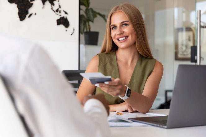 Woman smiling, handing over a bank card.