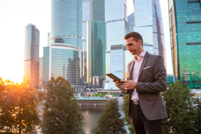 Businessman using tablet with skyscrapers in background