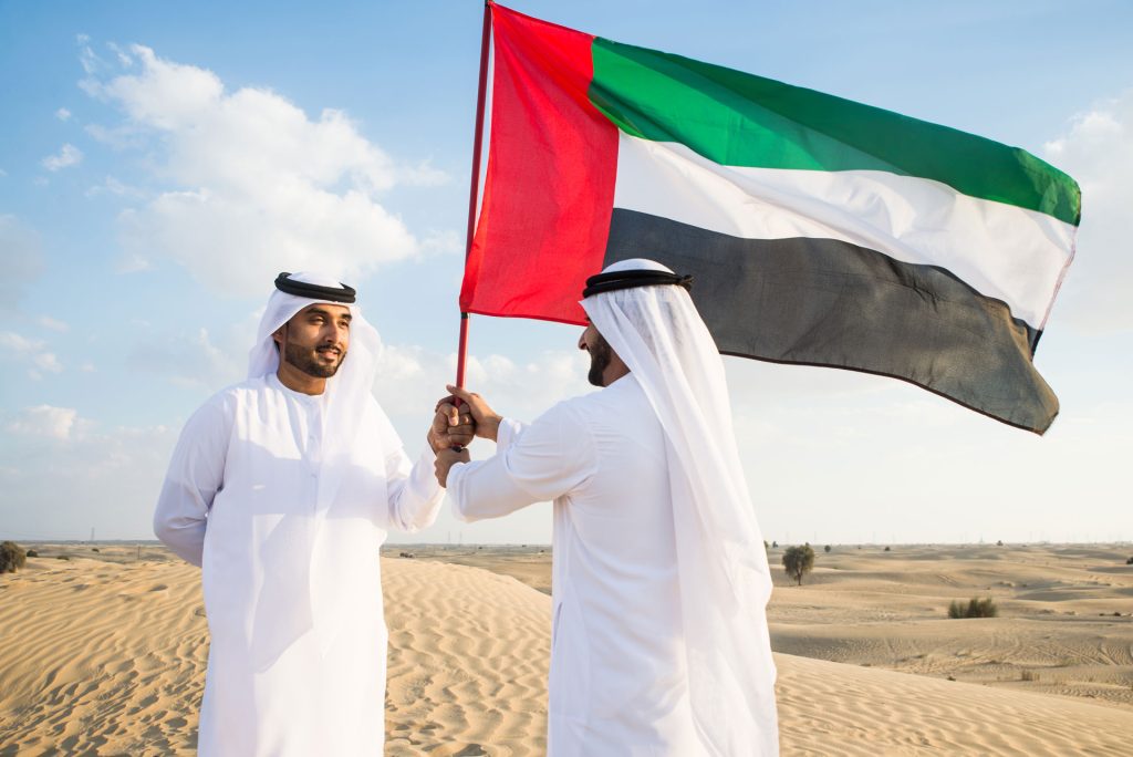 Two men with UAE flag in desert